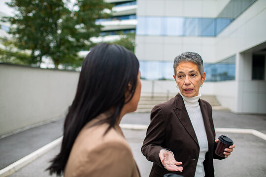 Two businesswomen discussing work outside office building