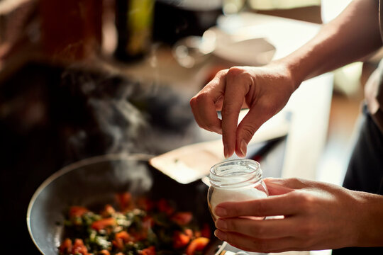 Home cook seasoning vegetables with salt in kitchen