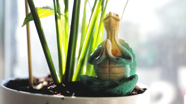A small toy turtle perched on a potted plant, perfect for decorative or educational use