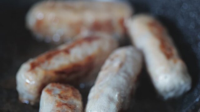 Savory sausages sizzling in a hot frying pan on a stove
