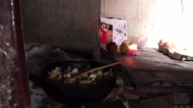 Cooking simple food on a rustic stove by candlelight in a dark hut