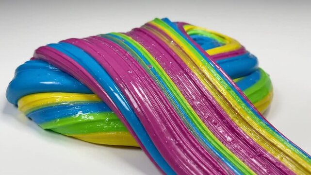 Rainbow slime being pulled showing vibrant colors and textures on a white surface for creative play and sensory exploration