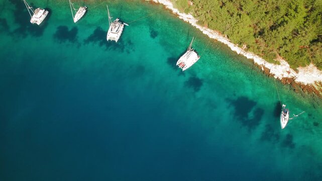 Yachts moored along wooded coastline in serene turquoise sea waters of Kefalonia
