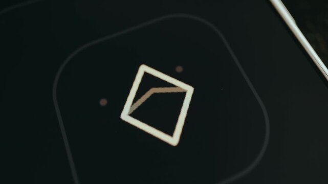 Graphic icon featuring a stylized square surrounded by small moving dots