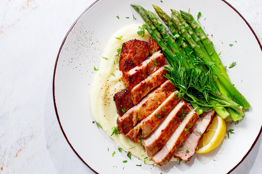 Sliced pork chop, with mashed potatoes and asparagus, on a white plate, homemade, no people,