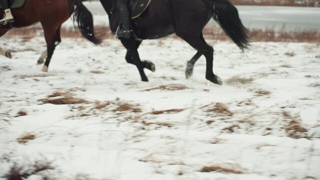Caucasian riders tandem gallop closeup across snowy field with flying snow and splashing hooves, intense training pace, focus on legs and hooves, raw power and rhythm captured in motion during outdoor