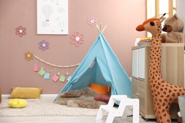 Colorful paper notes and beautiful decor hanging on beige wall near toy wigwam in stylish children's room. Interior design © New Africa