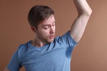 Obraz premium Man with sweaty armpits on brown background
