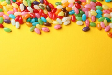 Obraz premium Delicious colorful candies on yellow background, top view. Space for text