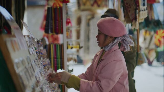 Two diverse tourists browse various souvenirs and local crafts at an outdoor city market stall. They are enjoying their travel experience while shopping for unique mementos.