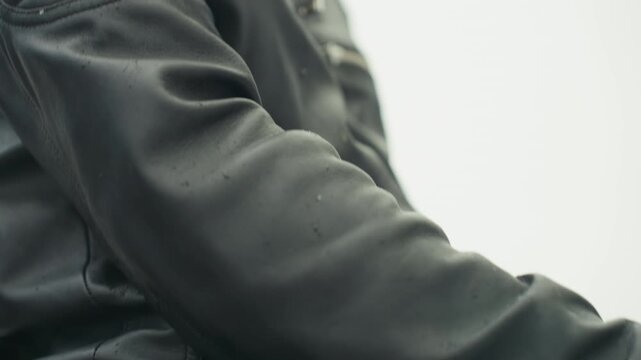 Detailed shot of perspiring leather sleeve with droplets and rider gear. Macro view of water droplets on leather jacket sleeve demonstrating outdoor riding attire and textured grain