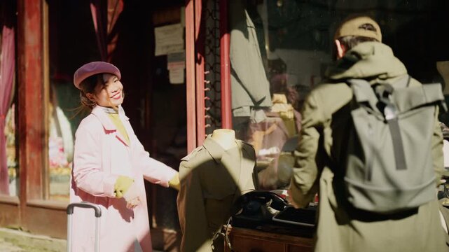 Diverse tourists enjoy discovering vintage items in a city shop window. A joyful couple looks at retro clothing and accessories in a storefront display.