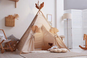 Stylish wigwam with dry leaves in child's room © New Africa