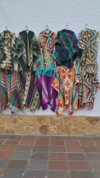 Colorful Patterned Ponchos Hanging on Street Market Wall Display.