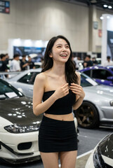 Fototapeta premium カスタムカーの展示会場で笑顔を見せる黒い衣装のレースクイーン