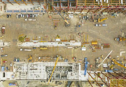 Aerial view of a large industrial construction site featuring steel frameworks, yellow cranes, and heavy machinery on a dirt ground in Taiwan.