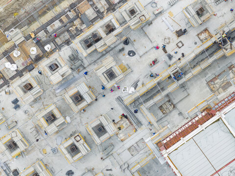 Aerial view of a busy construction site with workers in safety gear among concrete foundations and steel reinforcement in Taiwan.