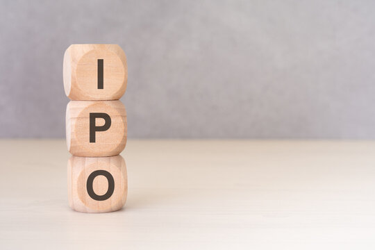 IPO - Initial Public Offering - acronym on vertically stacked wooden blocks. Minimalist financial concept.
