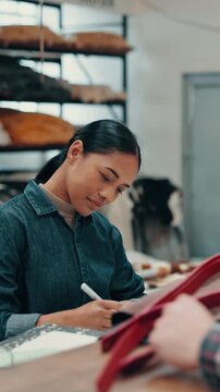 Woman, leathersmith and customer with belt in shop for fabric repair, design or checkout. Female person, artisan or crafter writing with invoice for service, item or product order on counter in store