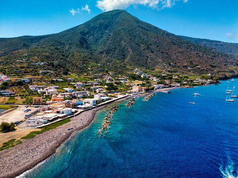 Aerial view of Salina island featuring the coastal village and volcanic mountain slopes under a clear blue sky in Metropolitan City of Messina, Sicily, Italy.