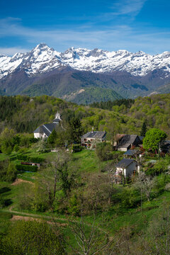 Mountain village in spring with snow-capped peaks in the background. Ariege Pyrenees France