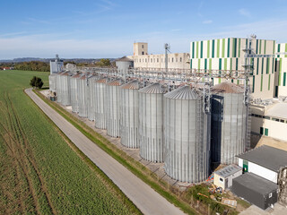 An aerial view of grain silos and agricultural storage facilities in a rural area with crops nearby. © 24K-Production