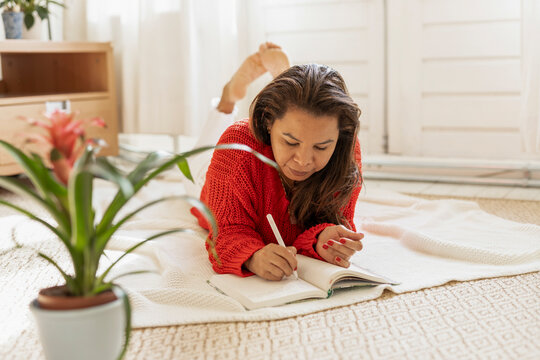 Woman lying on the floor writing