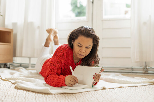 Woman lying on the floor writing