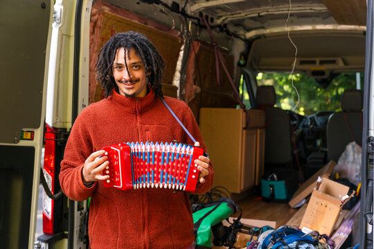 Man holding an accordion standing by moving van
