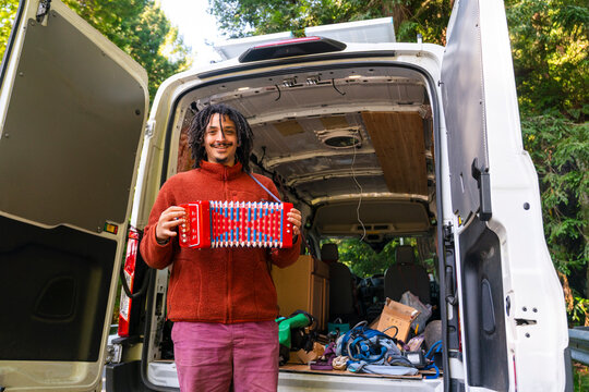 Man holding an accordion standing by moving van