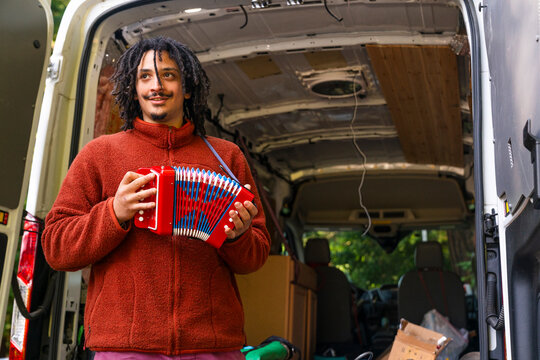 Man holding an accordion standing by moving van