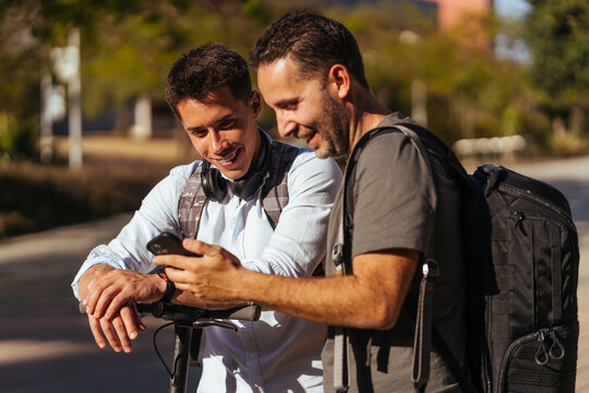 Satisfied young males with rucksack looking at screen
