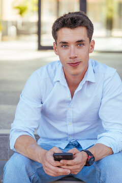 Young guy in shirt resting on porch and looking at camera