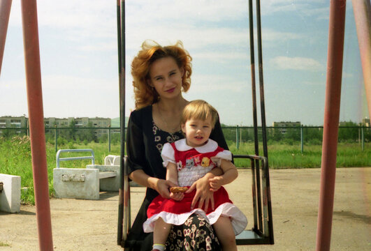 Mother and Child Sitting on Swing Outdoors