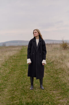 A woman stands peacefully in an open field