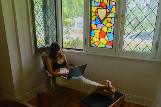 Woman walking with laptop and looking through the stained window 