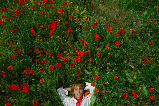 Colorful poppy field with a blue garment in the spring sunshine