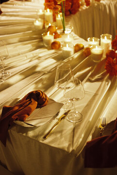 Elegant table setting with candles, glassware and orange accents