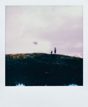 Polaroid of father and child flying kite on hill
