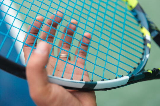 Close-Up of Hand Touching Tennis Racket Strings