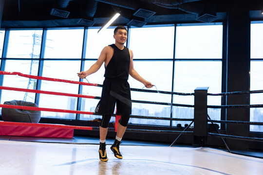 Male Boxer Jumping Rope in Boxing Ring at Modern Gym