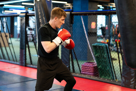 Male Boxer in Guard Stance Training by Heavy Bag in MMA Gym