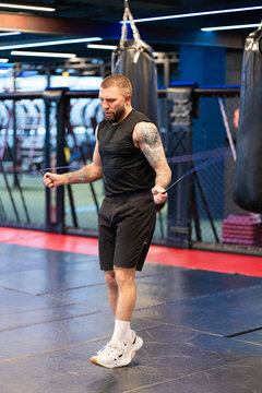 Tattooed Male Boxer Skipping Rope in Neon-Lit Boxing Gym
