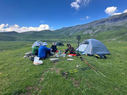 UGC group of hikers sitting down for snack while setting up camp. 