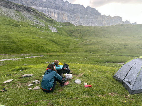 UGC of two hikers sitting down for snack while setting up camp. 