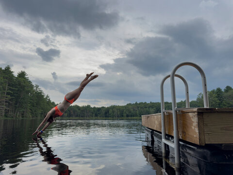 Teen diving off dock into lake 