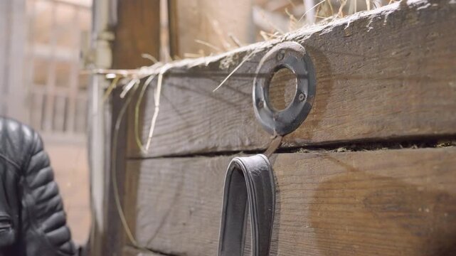 Closeup weathered wood and metal ring, leather strap being threaded through ring with subtle hand movement, soft sunlight and dust motes, tactile grain and patina, vintage barn workshop atmosphere