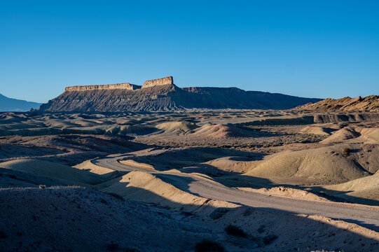 Backcountry road in rugged landscape between Factory Butte and North Caineville Mesa near Hanksville, Utah on crisp clear spring morning.