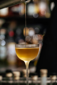 Cocktail being poured into a coupe glass