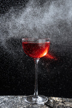 Red cocktail in coupe glass with spray mist